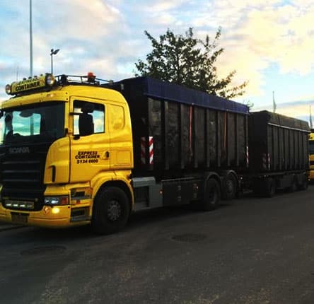 Gul og sort farvet lastbilcontainer på vej med letskyet blå himmel